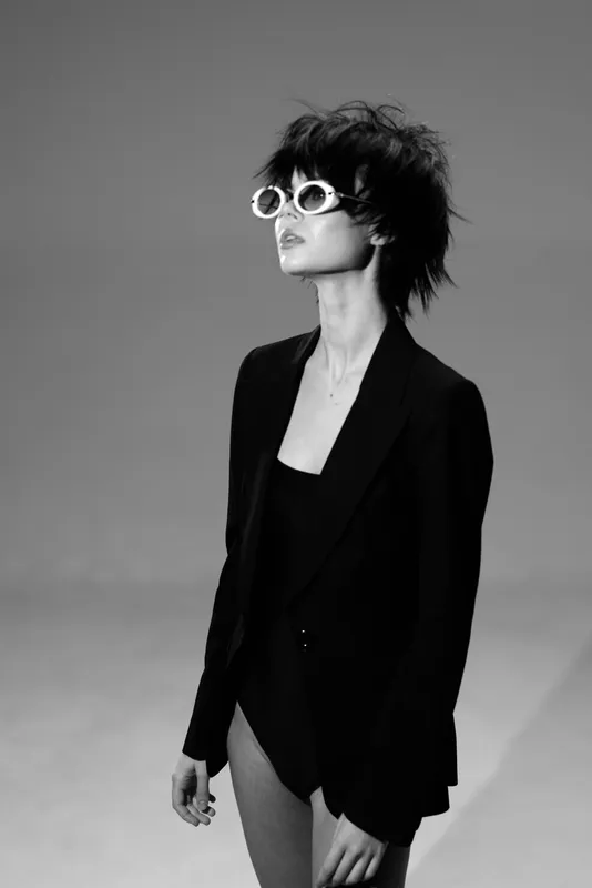 Fashionable woman wearing sunglasses and black jacket in stylish black and white portrait.