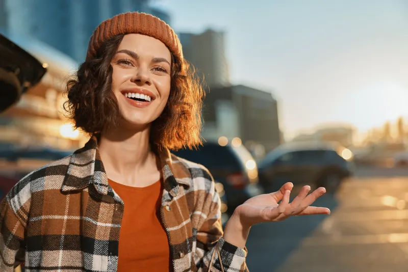 Woman with warm smile in urban city scene at golden hour, candid portrait conveying authenticity and mindful lifestyle, emotional storytelling through natural light and genuine joy.
