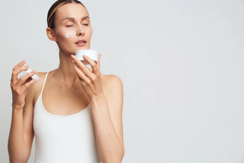 Woman skincare face moisturizer beauty cosmetic routine spa cream applying closeup portrait on white background, hands with cotton pads, gentle serum application, hydrated healthy skin
