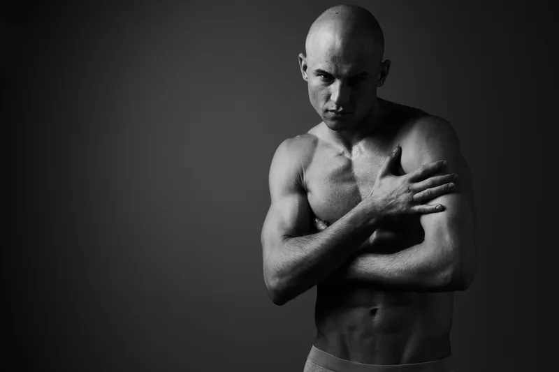 Black and white portrait of a muscular man, with intense expression and strong physique, showcasing emotion and strength, perfect for fitness and lifestyle themes.