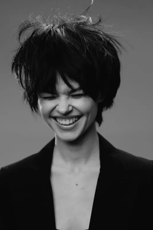smiling woman with short hair laughing in black and white portrait, joyful expression, natural beauty, casual style