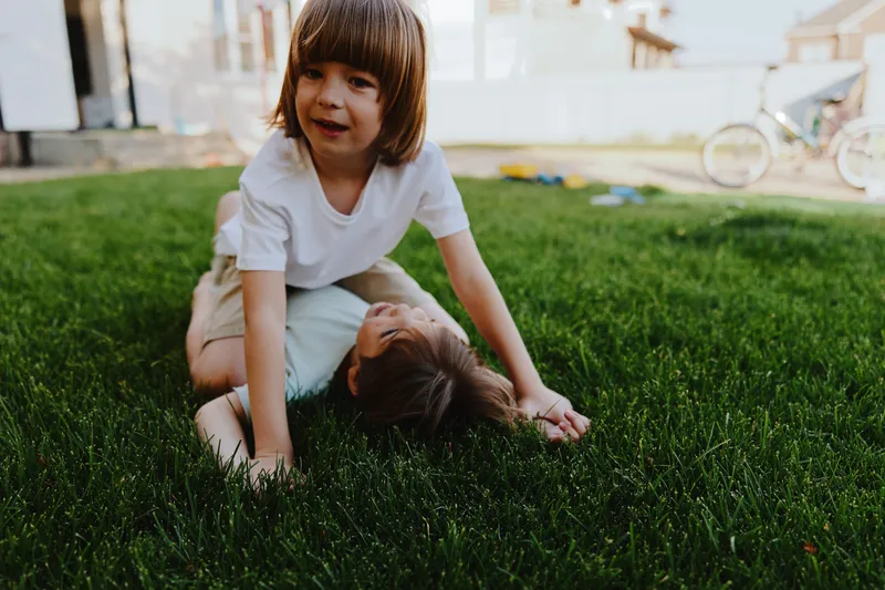 Active boys playing together on lush green grass, enjoying a warm sunny day filled with laughter and joy, highlighting childhood friendship and fun.