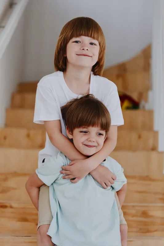Two cheerful boys playing together, one smiling from behind the other, capturing their joyful childhood memories. Perfect for family and children's themes.