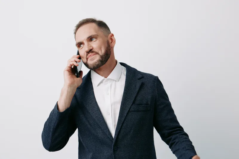 A confident business professional man on a phone call, showing focus and emotion, captured against an isolated colored backdrop to convey corporate mood and momentum.