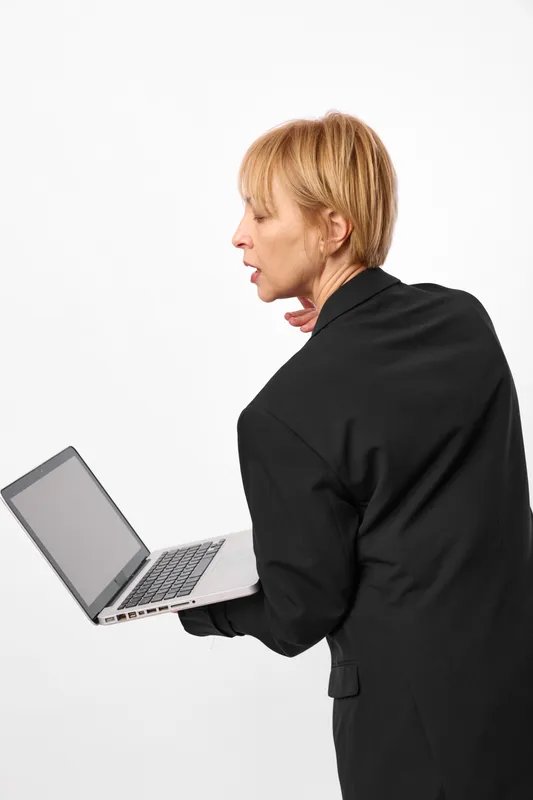 Woman working with a laptop in an office studio, technology and communication. Side profile typing on a laptop, digital business focus, professional jacket, white background, soft studio light