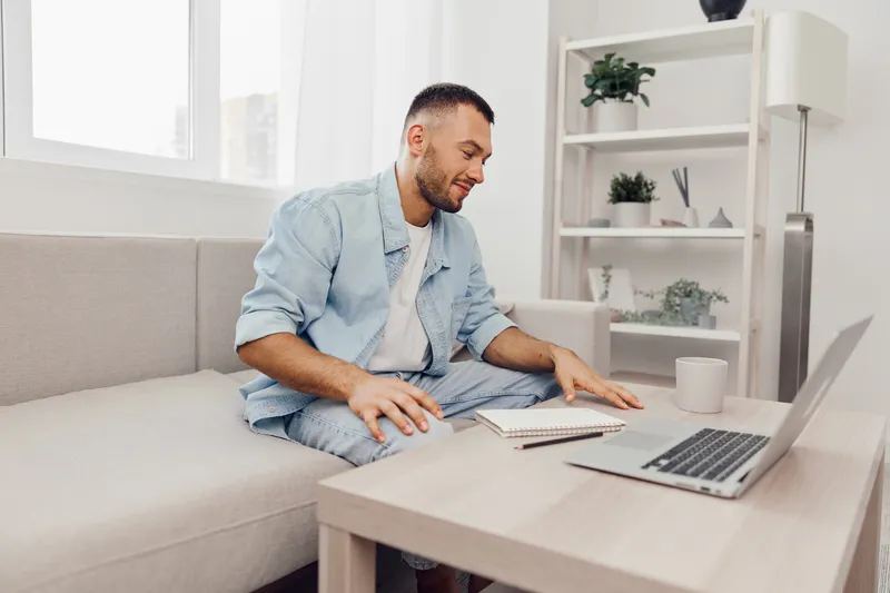 Smiling man working from home, casual attire, modern interior, engaged in online meeting, warm lighting, relaxing atmosphere, productivity boost.