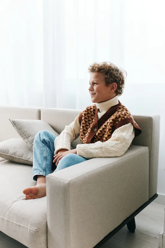 Authentic portrayal of a playful child at home, highlighting school readiness and wholesome lifestyle through a relaxed pose, cozy furnishings, and natural light.