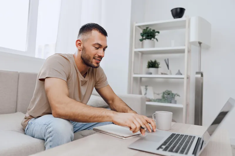 Engaged man working on a laptop in a cozy living room, showcasing modern design elements and a calming atmosphere ideal for productivity and creativity.