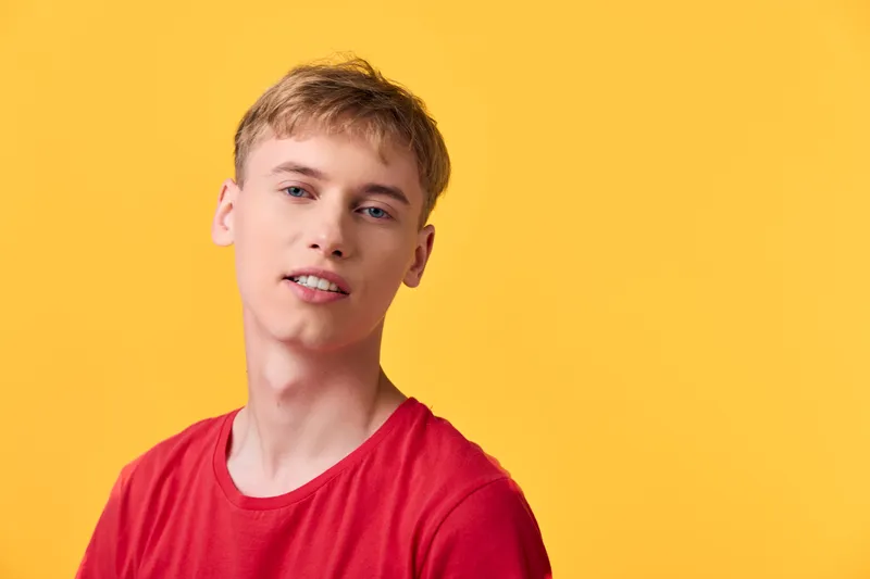 young man, red shirt, yellow background, studio shot, casual pose, bright lighting, cheerful mood, fashion vibe, advertising ready, candid style, modern look, versatile usage for branding and