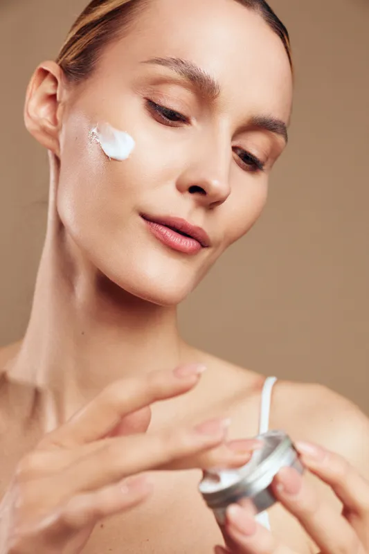 Woman skincare face cream beauty treatment cosmetic spa hygiene moisturizer concept, closeup portrait of adult woman applying facial cream with cotton pad, soft smooth skin, spa mood