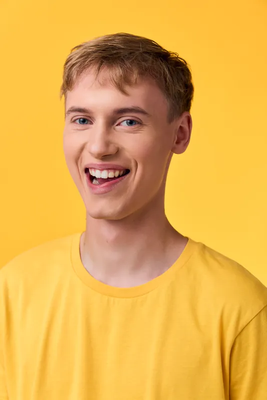 Smiling man in a yellow shirt against a bright yellow background, conveying cheerful casual style, warm lighting, and friendly mood perfect for lifestyle, fashion, and upbeat stock imagery
