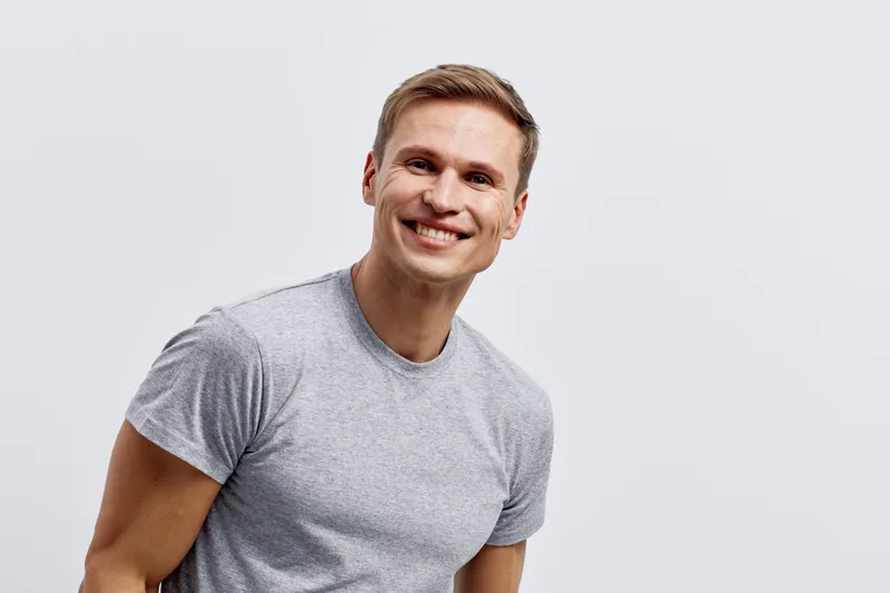 smiling happy young caucasian man wear grey t-shirt look camera digital nomad concept technology casual portrait isolated on plain background