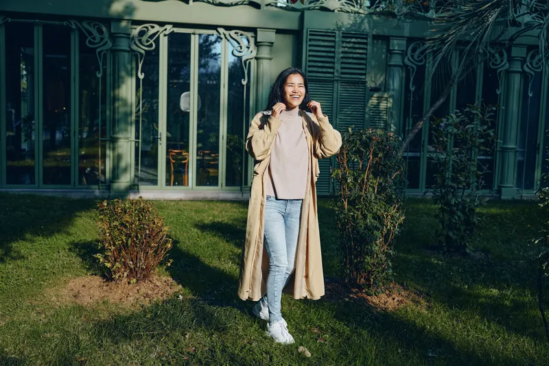 Coat, woman, outdoor, garden, fashion, lifestyle, smiling, casual, clothing, pose in sunny yard with modern glass doors, greenery and lawn setting, stylish streetwear shown in natural light and