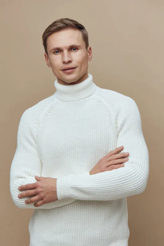 confident man in white turtleneck sweater standing folded arms looking at camera studio portrait digital detox mental health concept
