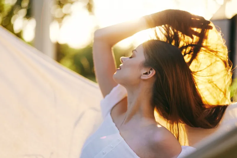 A serene young woman with flowing hair basking in golden sunlight, embodying joy and freedom in a lush outdoor setting
