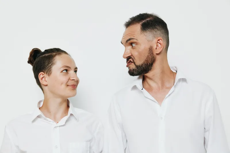 A professional man exudes confidence and focus while engaging with a colleague, set against a solid colored background that emphasizes business mood and teamwork.