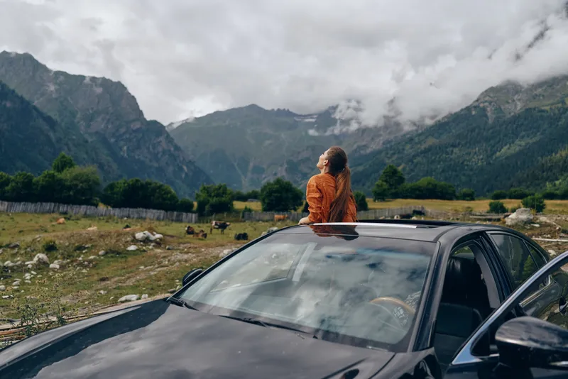 woman on car roof mountains travel nature roadtrip outdoors adventure authentic inclusive