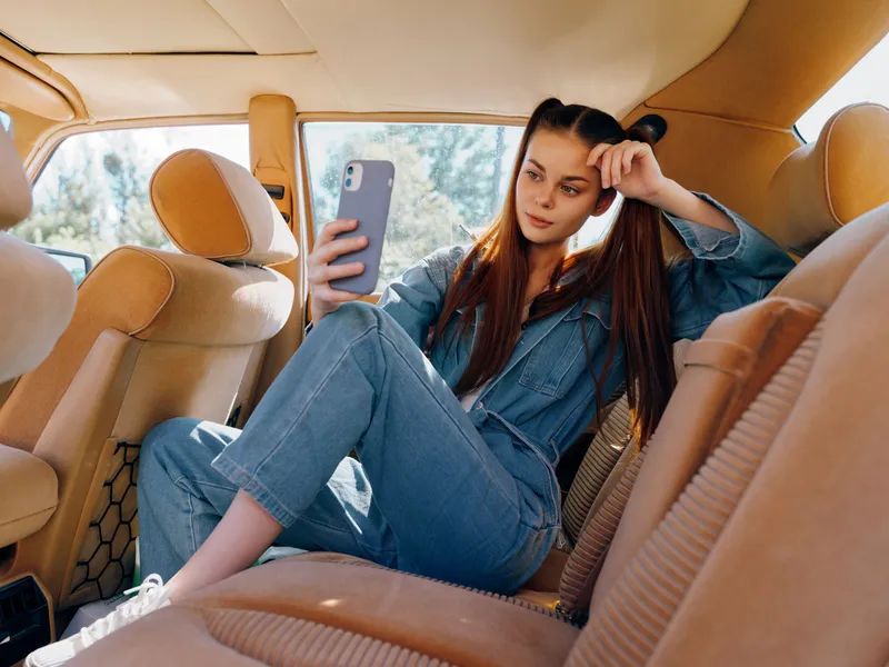 Young woman in casual denim outfit taking a selfie in a car, expressing relaxed vibes and enjoying a sunny day, perfect for lifestyle and social media themes.