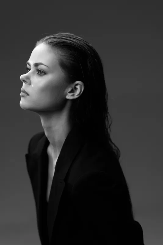 Black and white portrait of a serious woman with wet hair wearing a dark blazer in profile view.