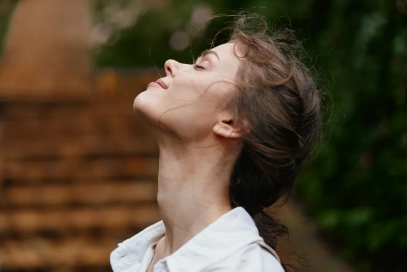 A serene young woman enjoying nature outdoors in a lush green environment, captured in a moment of tranquility and self reflection, embracing peacefulness and calmness