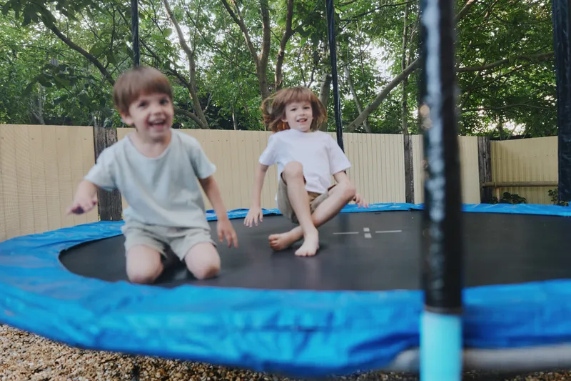 Joyful children playing on a trampoline, filled with laughter and energy, creating a lively atmosphere of fun under sunny skies. A snapshot of childhood bliss.