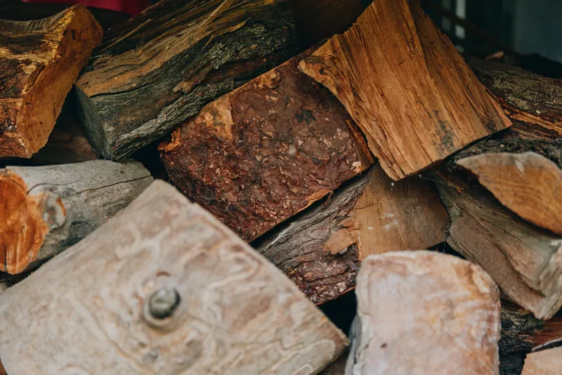 Firewood wood logs stacked wood split logs fireplace rustic pile of seasoned oak near rural cabin, autumn scene, middle-aged bearded homeowner prepping winter fuel and cozy stove.