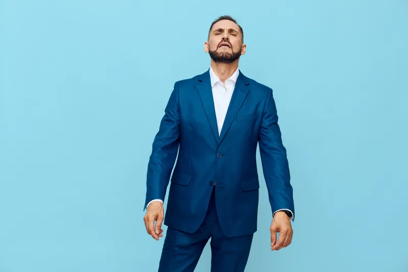 A professional man in a sharp blue suit stands against a solid colored blue backdrop, radiating confidence, focus, and determination. Perfect for corporate or business themes, leadership, and success.