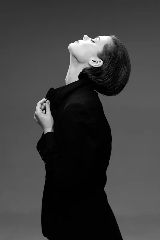 Black and white profile of a stylish woman in jacket expressing elegance and confidence with dramatic posture