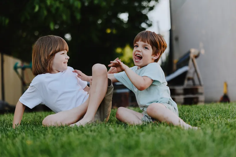 Playful children enjoying a sunny day, laughing and playing together in a green garden, creating joyful moments of childhood camaraderie and happiness.