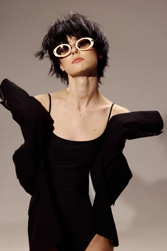 stylish woman wearing sunglasses and black dress posing with confident and edgy look