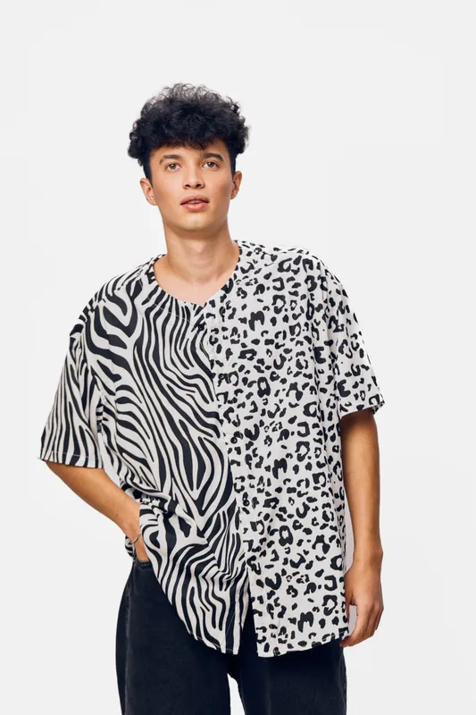 young man wearing half zebra, half leopard print shirt posing against a plain white background with casual style and natural curly hair, modern fashion concept