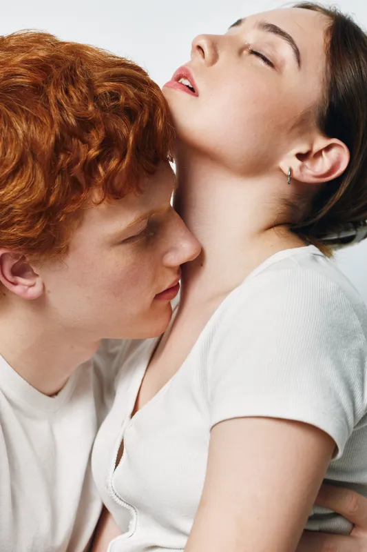 Couple, intimacy, affection, and love with man and woman embracing closely in white clothing at studio. Closeup, red hair, emotional connection and tenderness between two people.