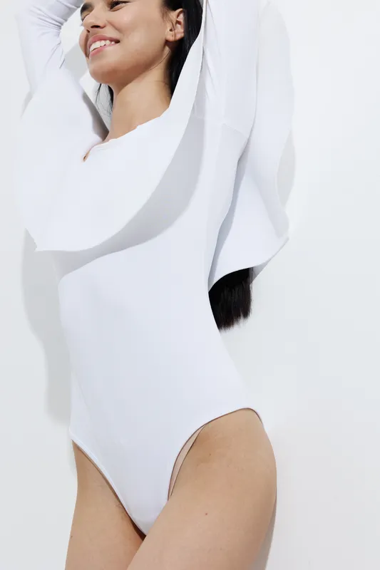 athletic woman sport fitness wearing fitted white bodysuit smiling with joy, healthy lifestyle concept, modern minimalistic studio background, bright lighting