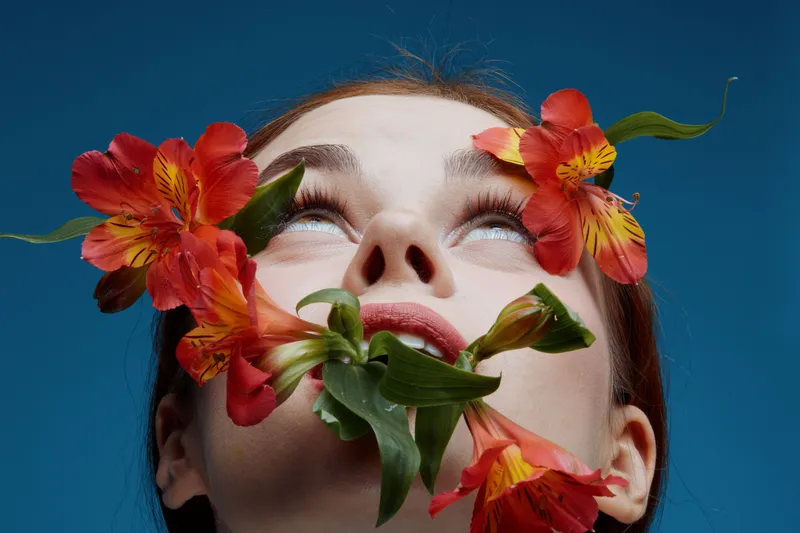 Woman With Red Flowers, Expressing Serenity Against a Blue Background