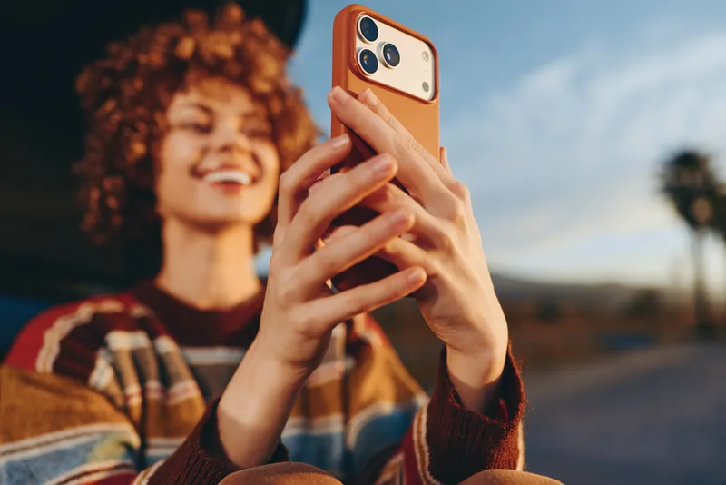 Woman lifestyle outdoors, portrait of hands holding smartphone, technology for communication, casual sweater and curly hair, smiling woman blurred in background, candid moment in sunlight