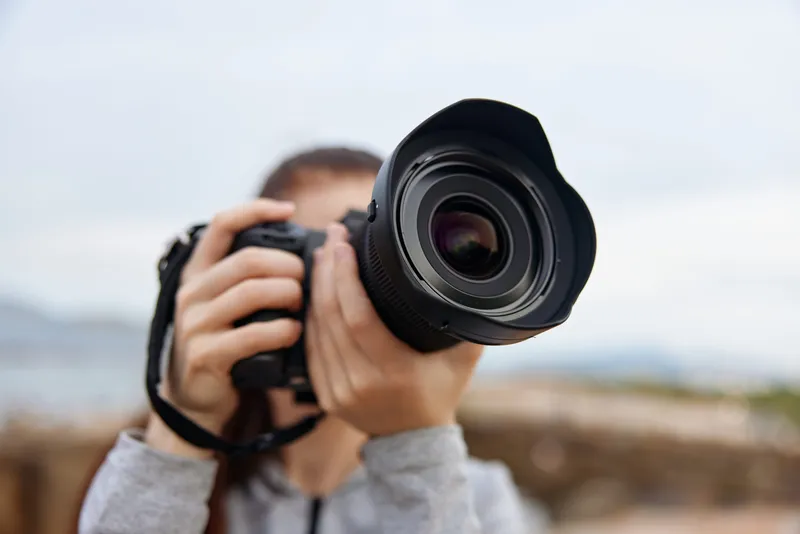 A young female photographer capturing nature scenes with a DSLR camera, showcasing passion and creativity in a serene outdoor setting