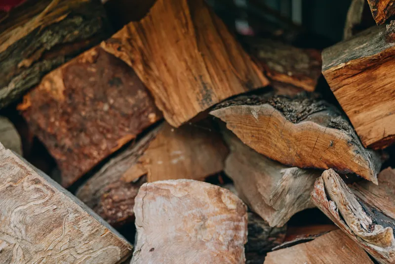Firewood, wood, logs, chopped wood, stacked wood, timber in rustic pile for fireplace, closeup texture and grain of natural seasoned cut logs ready for burning and winter heating supply.