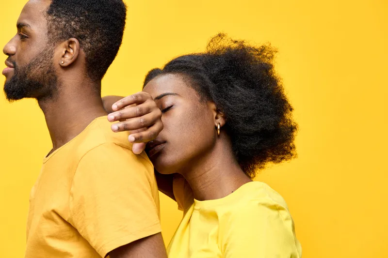 A joyful couple sharing a loving moment against a vibrant yellow background, showcasing intimacy and connection in stylish yellow outfits