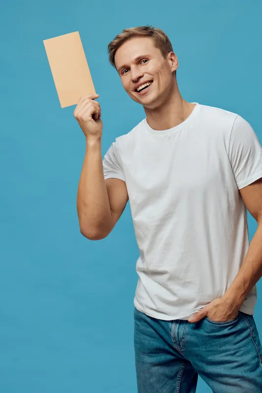 smiling caucasian man holding envelope wearing white t-shirt casual outfit blue background cheerful expression concept digital detox mental health