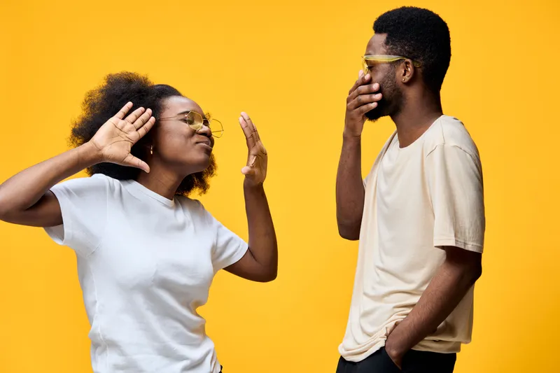 Happy young couple expressing joy against a bright yellow background, showcasing modern casual fashion and playful emotions for lifestyle photography
