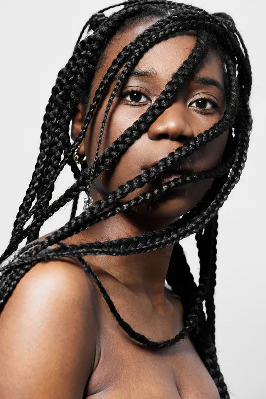 Portrait of a confident young woman with braided hair, conveying strength and beauty against a minimalistic background in soft tones
