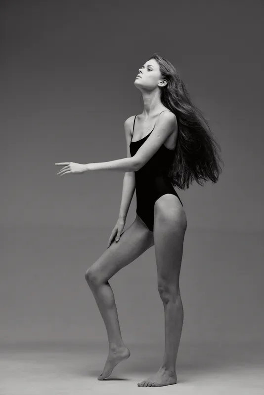 Black and white elegant woman posing in swimsuit with flowing hair, graceful posture, studio background