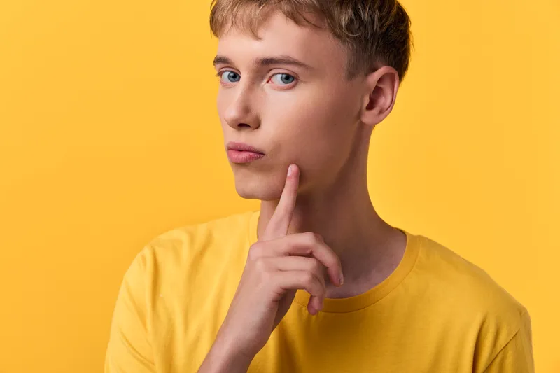 Thinking man in a yellow shirt on a solid yellow background, thoughtful pose and contemplative mood, focus on ideas and decision making, studio concept image for intellect and creativity