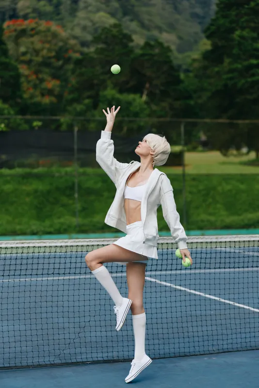Young female tennis player in stylish sportswear enjoying a sunny day on the court, embodying athleticism and grace while holding tennis balls