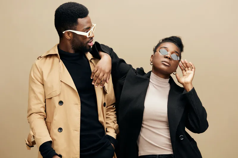 Stylish couple in contemporary fashion expressing confident emotions against a neutral background, showcasing urban aesthetics and modern style