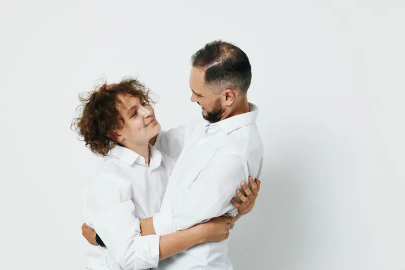 A professional man in business attire shares a warm moment with a colleague, showing confident and calm emotion against an isolated colorful background.