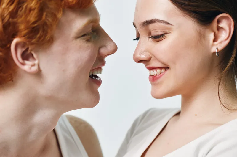 Couple closeup, smiling and looking at each other with joy and affection, happy young people expressing love and connection in a bright room with gentle emotions.