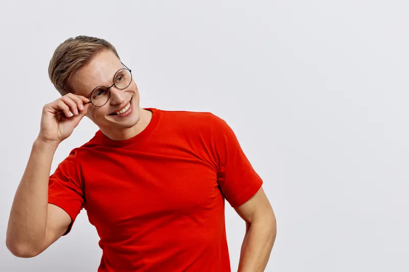 smiling young man wear red t-shirt glasses look aside isolated plain white background casual style positive emotions concept digital nomad