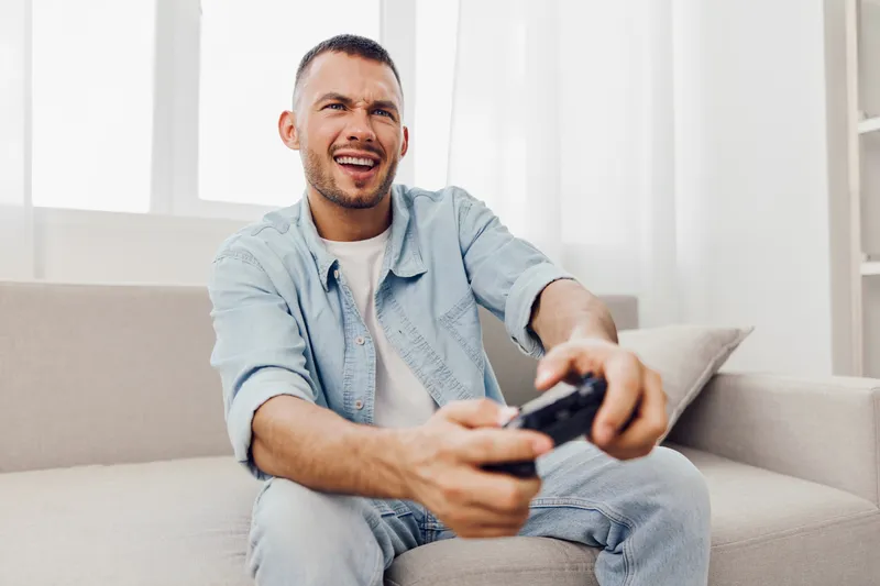 A man enjoying a digital detox while playing video games, reflecting on his work-life blur and embracing emotional minimalism amidst technology fatigue.