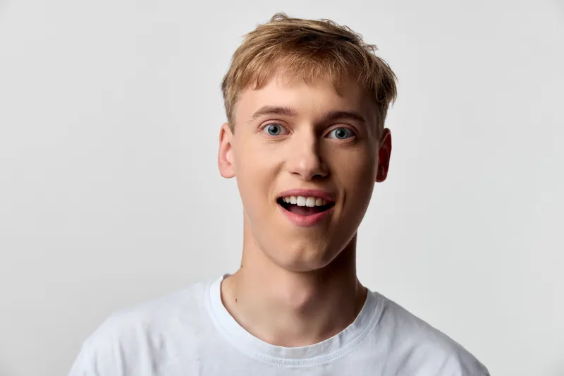 Surprised man in a white t shirt reacts with wide eyes and open mouth, capturing a spontaneous energetic moment suitable for reactions, lifestyle, social media, or advertising content
